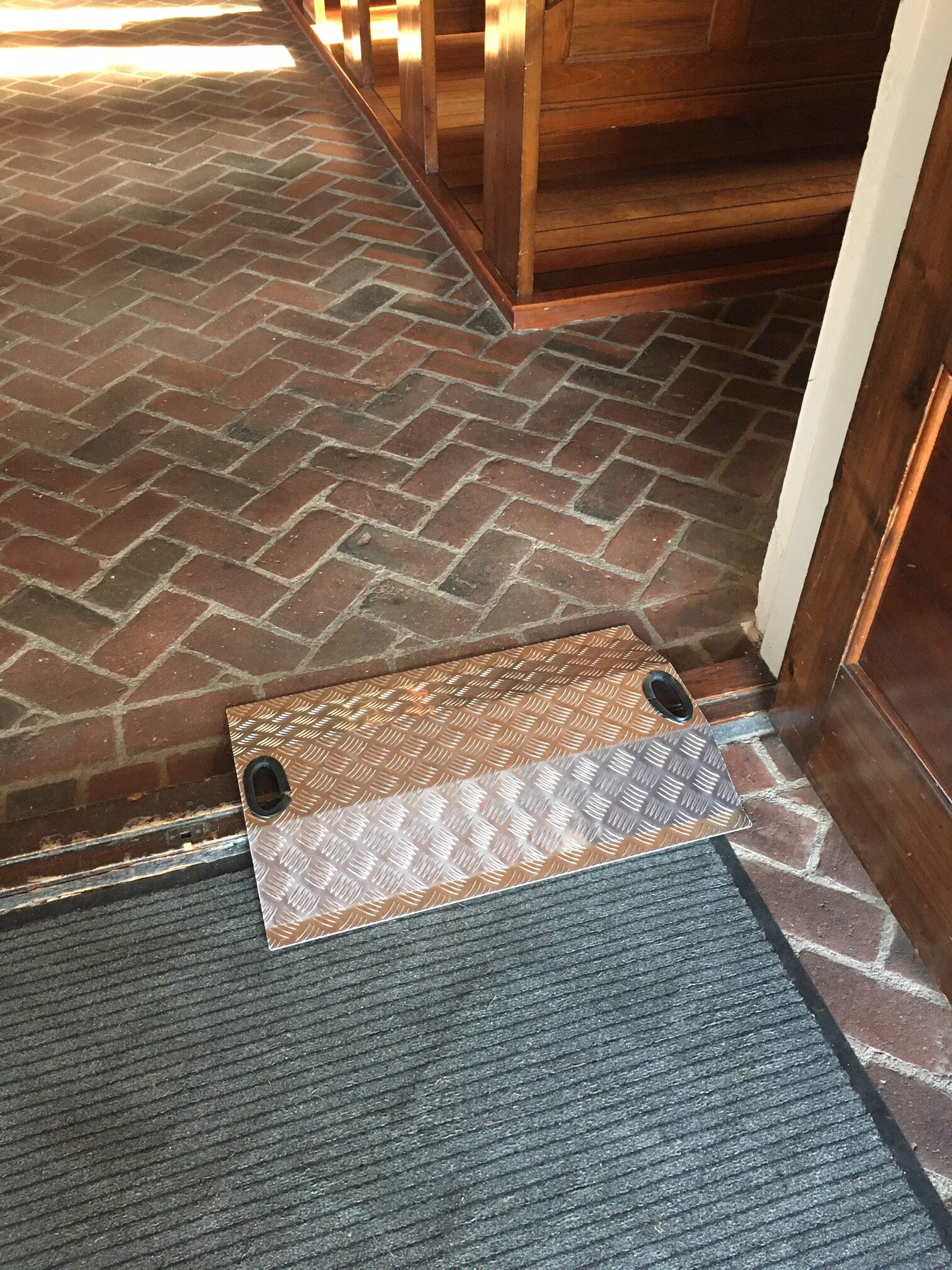 På billedet ser du vores dørtrinsrampe i aktion. Rampen er placeret ved siden af et højt dørtrin og giver en jævn og sikker overgang. Den skridsikre overflade sikrer et solidt greb, og den holdbare konstruktion garanterer langvarig ydeevne. Med denne dørtrinsrampe kan du nemt og sikkert krydse dørtrin og nyde en ubesværet adgang til forskellige rum og områder.